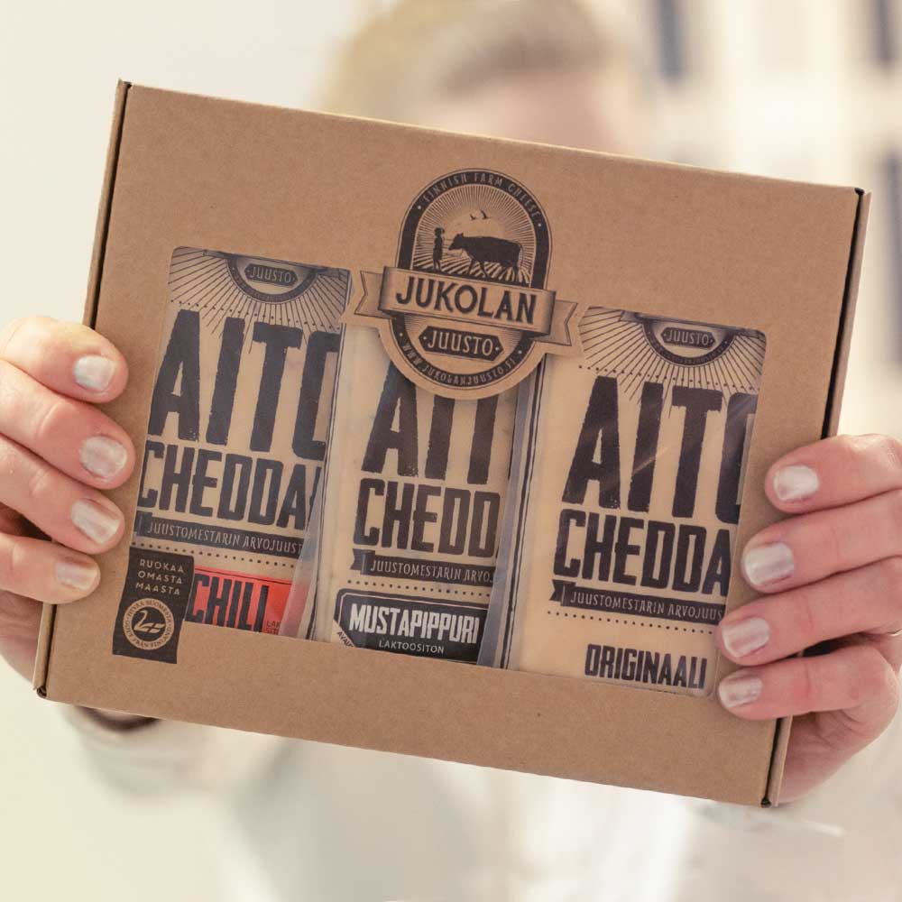 joululahja_yrityksille_juusto_cheddar_sisältö Jukolan Juuston lahjapakkaus käsissä